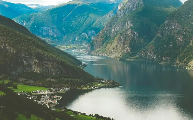 Fjord tussen steile groene bergen met een dorpje aan het water